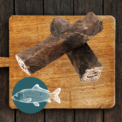 Two Wolf Fish Stick Chews for dogs sit on a cutting board
